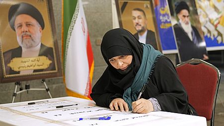 Uma mulher vota durante as eleições presidenciais numa mesa de voto dentro da embaixada iraniana em Bagdade, Iraque, sexta-feira, 28 de junho de 2024. 