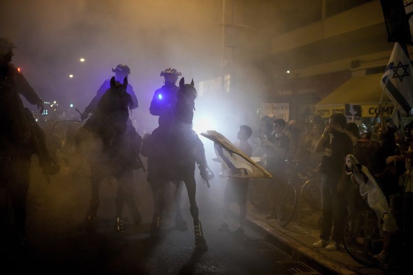 Israeli mounted police officers disperse demonstrators blocking a road during a protest against Israeli Prime Minister Benjamin Netanyahu's government, June 2024