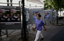 Uma mulher passa por painéis de campanha para as próximas eleições parlamentares em Paris, sexta-feira, 21 de junho de 2024. (AP Photo/Christophe Ena)