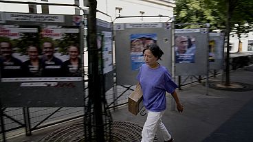 Uma mulher passa por painéis de campanha para as próximas eleições parlamentares em Paris, sexta-feira, 21 de junho de 2024. (AP Photo/Christophe Ena)