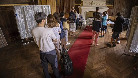 People wait in a polling station to vote in the first round of the French parliamentary election, in Paris