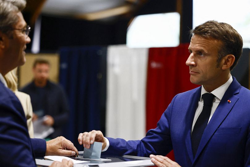 French President Emmanuel Macron, right, casts his ballot to vote in the first round of the early French parliamentary election, in Le Touquet-Paris-Plage, northern France.