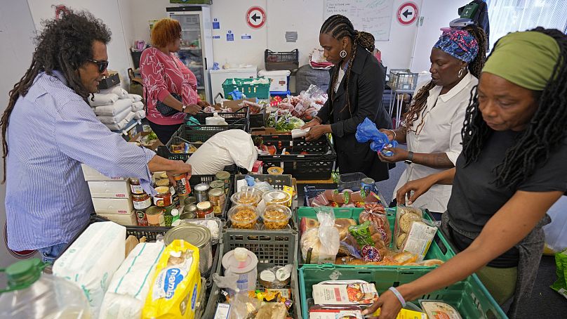 Michelle Dornelly, segunda desde la derecha, y varios voluntarios preparan comida antes de la apertura del Community Food Hub en Hackney, Londres, el jueves 13 de junio de 202
