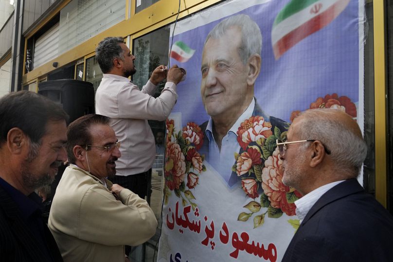 Un partidario del candidato reformista Masoud Pezeshkian pega su cartel en una puerta durante un mitin de campaña en Teherán, junio de 2024.