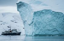 A ship goes past an Iceberg in Arctic waters.