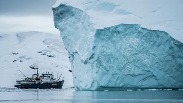 A ship goes past an Iceberg in Arctic waters.