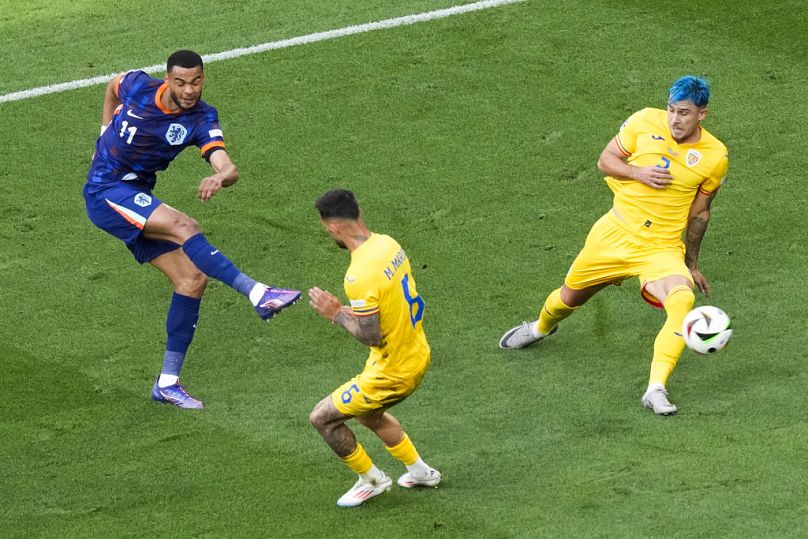 Cody Gakpo, left, scores the opening goal against Romania's Marius Marin and Andrei Ratiu during a round of sixteen match between Romania and the Netherlands