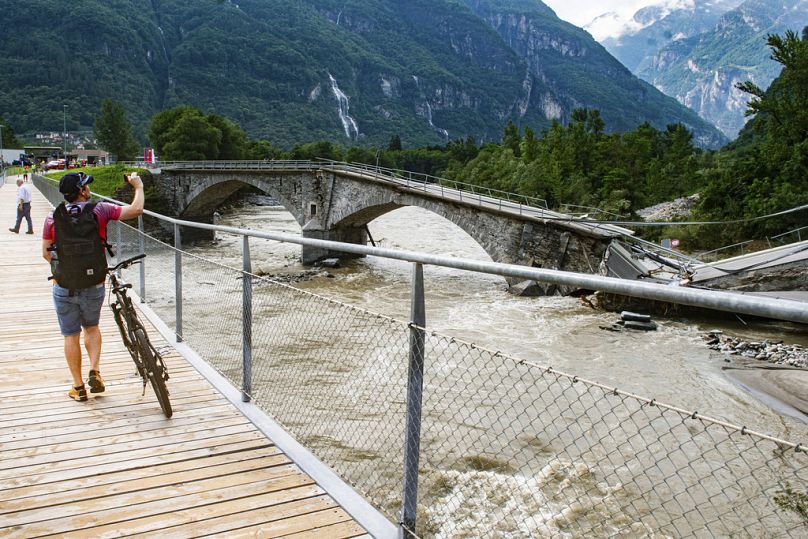 A man takes a photo of the collapsed Visletto bridge between Visletto and Cevio, in the Maggia Valley, 30 June 2024
