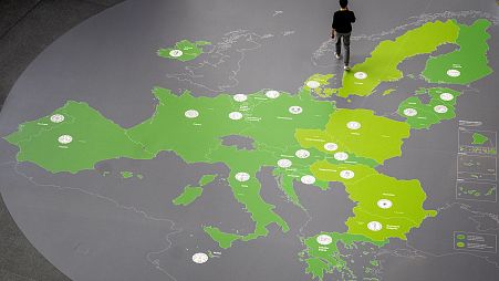 رجل يمشي على خريطة تظهر دول منطقة اليورو في رواق البنك المركزي الأوروبي في فرانكفورت بألمانيا