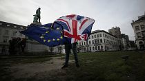 Peter Cook, apoiante pró-UE, desfralda uma bandeira da União e da UE antes de uma cerimónia para celebrar a amizade entre o Reino Unido e a UE, em frente ao Parlamento Europeu, em Bruxelas.