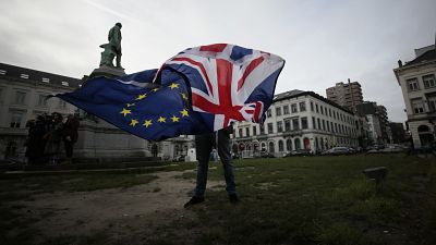 Peter Cook, apoiante pró-UE, desfralda uma bandeira da União e da UE antes de uma cerimónia para celebrar a amizade entre o Reino Unido e a UE, em frente ao Parlamento Europeu, em Bruxelas.
