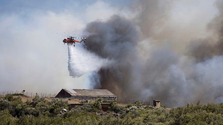 Un helicóptero de bomberos lanza agua sobre un incendio forestal en la zona de Keratea, al sureste de Atenas, Grecia, domingo 30 de junio de 2024.