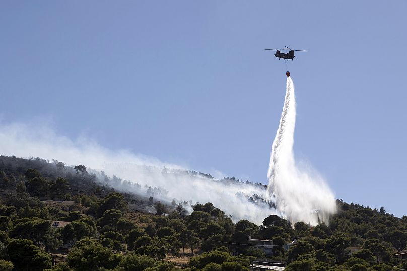 A firefighting helicopter throws water over a wildfire at Keratea area, southeast of Athens, Greece.