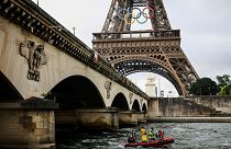 Bir kurtarma botu Seine Nehri üzerinde, Olimpiyat halkalarıyla süslenmiş Eyfel Kulesi'nin altından geçmektedir.