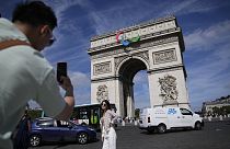 A tourist takes a photograph of the Arc de Triomphe which is currently featuring a Paralympic Games symbol ahead of the event