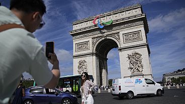 Um turista tira uma fotografia do Arco do Triunfo, que está atualmente a exibir um símbolo dos Jogos Paraolímpicos antes do evento