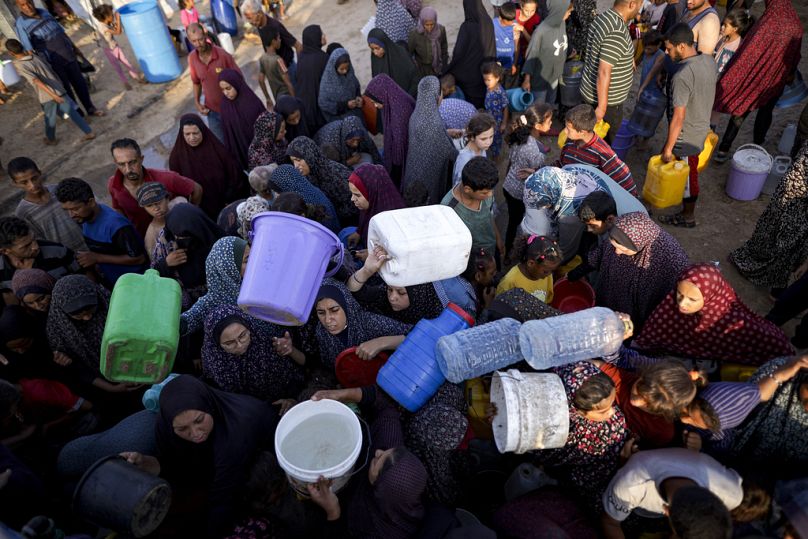 Palestinianos deslocados fazem fila para obter água num acampamento improvisado na cidade de Khan Younis. 1 de julho 2024