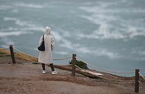 A person watches the sea from the top of a cliff at Praia do Norte, or North Beach, in Nazare, Portugal, Monday, Jan. 9, 2023.