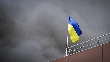 Le drapeau ukrainien flotte alors que de la fumée s'élève après l'attaque de missiles russes à Dnipro, en Ukraine, le mercredi 3 juillet 2024. (Administration régionale de Dnipro via AP)