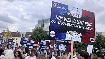 People gather against anti semitism, one carrying a placard reading "our lives worth more that an imported conflict" Thursday, June 20, 2024 in Paris. The alleged rape of a 12