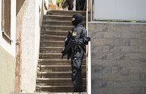 A police officer stands in front of a door with a submachine gun in Althengstett, 4 June 2024