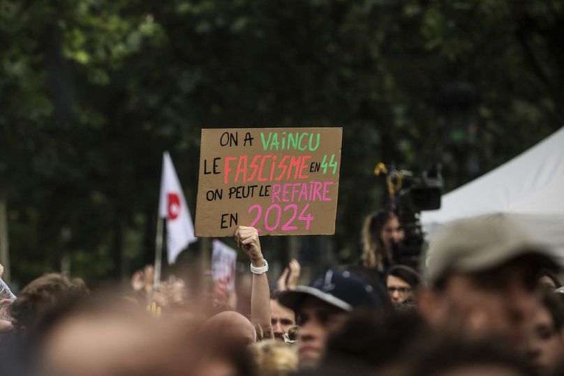 A person hods a placard reading "We defeated fascism in 1944, we can do it again in 2024" during a gathering at Republique plaza in a protest against the far-right