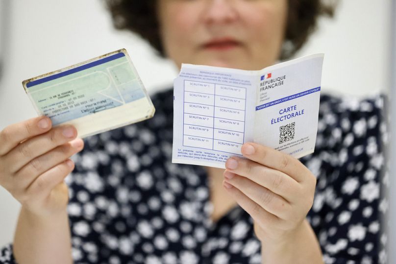  A voting assistant checks the voting card, right, and an identity card in Strasbourg, 30 June 2024