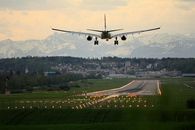 A plane lands near the striking Alps mountain range