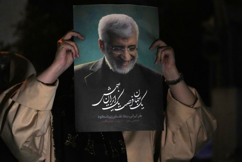 A supporter of Iranian presidential candidate Saeed Jalili holds up a poster of Jalili during his campaign stop in Tehran, 26 June 2024