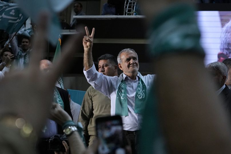 Iranian presidential candidate Masoud Pezeshkian and his supporters flash the victory sign during a campaign stop in Tehran, 23 June 2024