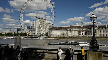 People have their pictures taken on the north bank of river Thames, against the backdrop of the London Eye, in London, Monday, June 17, 2024. (AP Photo/Alberto Pezzali)