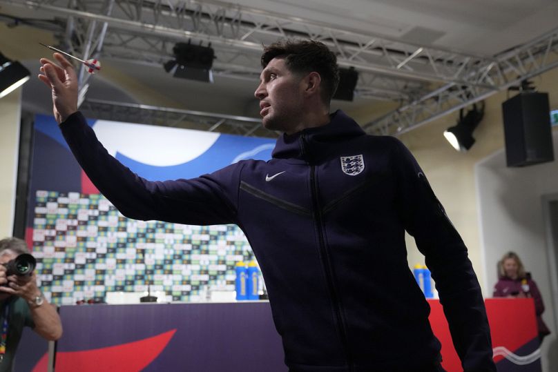 England's John Stones plays darts against a journalist before a press conference in Blankenhain, Germany, Thursday, July 4, 2024 