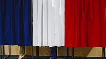 El presidente francés, Emmanuel Macron, y su esposa, Brigitte Macron, en la cabina electoral antes de votar.