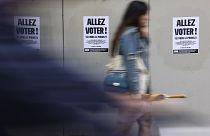 Uma mulher passa por um cartaz onde se lê "Vote" antes da segunda volta das eleições, no domingo, 7 de julho de 2024