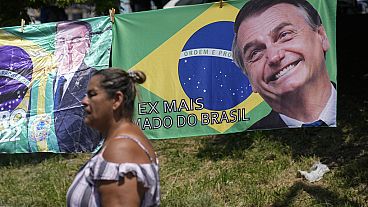 Una mujer pasa junto a una pancarta con la bandera nacional brasileña y una imagen del expresidente Jair Bolsonaro.