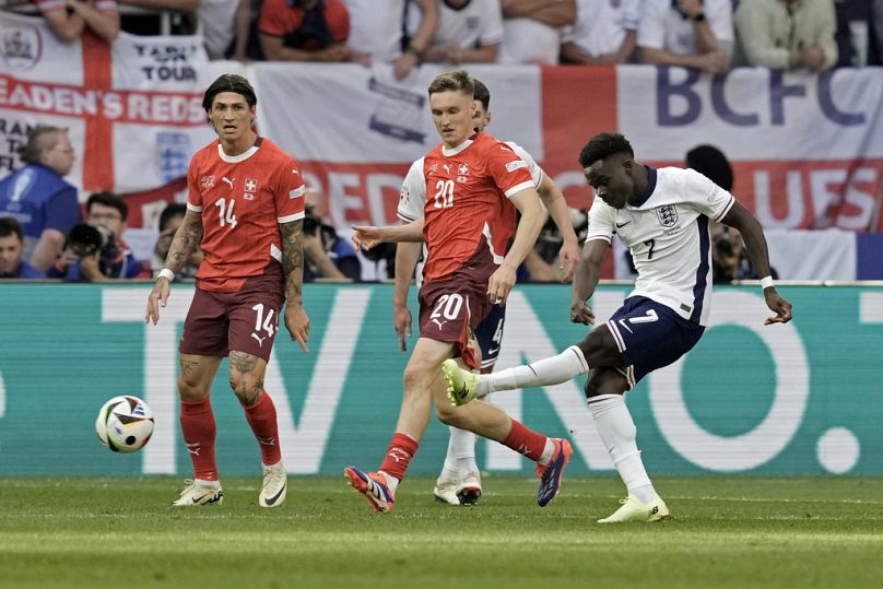 Bukayo Saka, da Inglaterra, remata para marcar o primeiro golo da sua equipa durante um jogo dos quartos de final entre a Inglaterra e a Suíça no Euro 2024