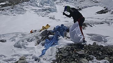 This image provided by the Peak Promotion shows a member of the Nepal government-funded team using a spade to remove frozen trash en route the Mount Everest, Nepal.