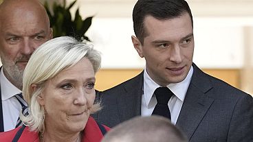 O presidente do partido de extrema-direita Rally Nacional, Jordan Bardella, à direita, sai com a líder de extrema-direita Marine Le Pen após uma conferência de imprensa.