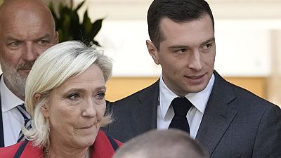 Far-right National Rally party president Jordan Bardella, right, leaves with far-right leader Marine Le Pen after a press conference.