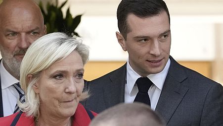 O presidente do partido de extrema-direita Rally Nacional, Jordan Bardella, à direita, sai com a líder de extrema-direita Marine Le Pen após uma conferência de imprensa.