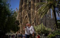 Un couple pose pour une photo devant la basilique Sagrada Familia conçue par l'architecte Antoni Gaudi à Barcelone, Espagne, vendredi 9 juillet 2021.