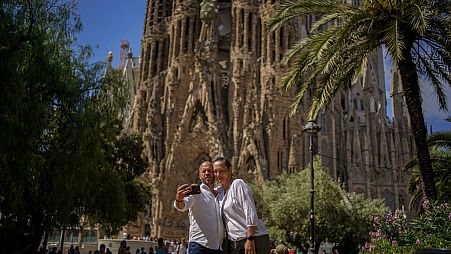 Ein Paar posiert für ein Foto vor der Basilika Sagrada Familia des Architekten Antoni Gaudi in Barcelona, Spanien, Freitag, 9. Juli 2021