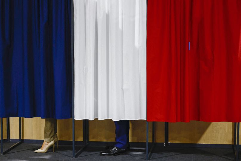 French President Emmanuel Macron and his wife Brigitte Macron stand in the voting booth before voting in Le Touquet-Paris-Plage, June 30, 2024