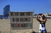 صورة على شاطئ في برشلونة كتب عليها "لا نريد سياحا في مبانيناهذا ليس منتجعا"