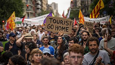Rund 500 Einwohner Barcelonas protestieren gegen den Massentourismus während einer Ausstellung von Formel-1-Rennwagen in der spanischen Stadt.