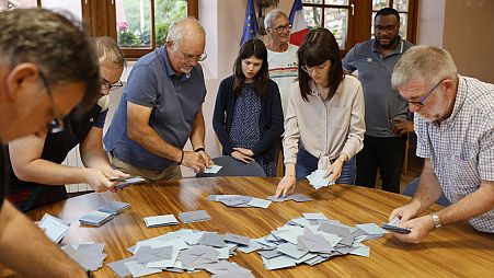 Assistentes de voto contam os boletins de voto numa assembleia de voto em Soultz-Les-Bains, no leste de França, domingo, 30 de junho de 2024