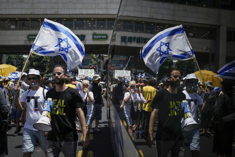 Demonstrators march with Israeli flags during a protest calling for the release of hostages held in the Gaza Strip by Hamas, 7 July 2024