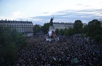 Des personnes se tiennent sur la place de la République en France et réagissent à la projection des résultats du second tour des élections législatives.