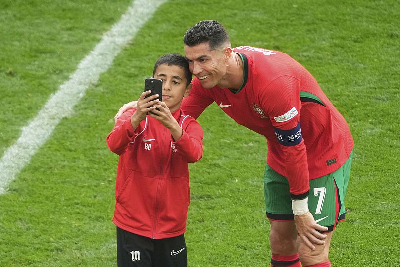 A young pitch invader takes a selfie with Portugal's Cristiano Ronaldo during a group match at the Euro 2024 football tournament in Germany.