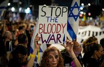 إسرائيلية تتحمل لافتة كتب عليها أوقفوا الحرب الدموية في مظاهرة لأهالي الأسرى والرهائن في تل أبيب
